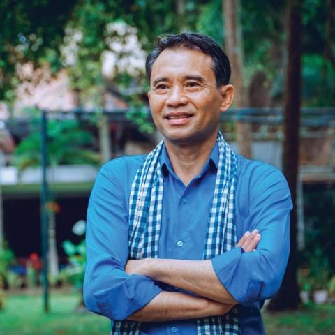 Man smiling in blue shirt with arms crossed