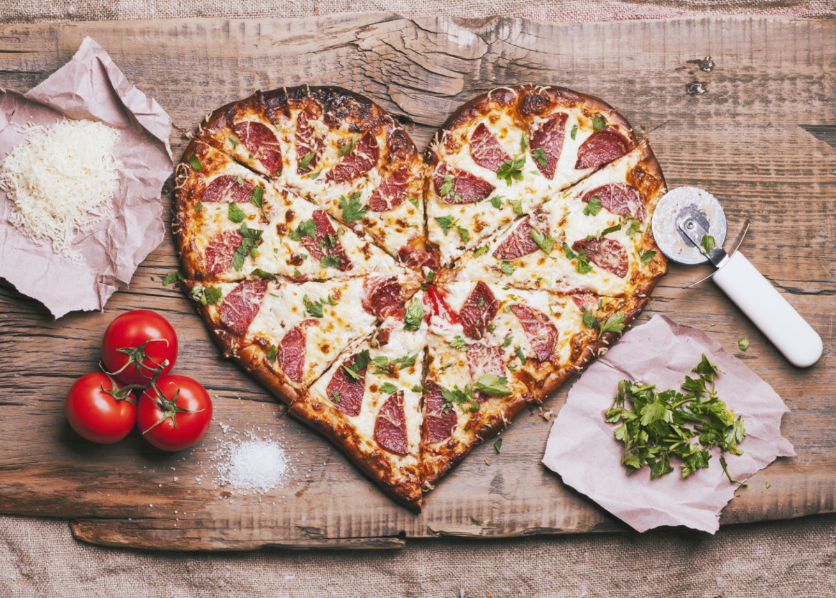 photo of a heart shaped pizza, tomatoes, slicer and parsley